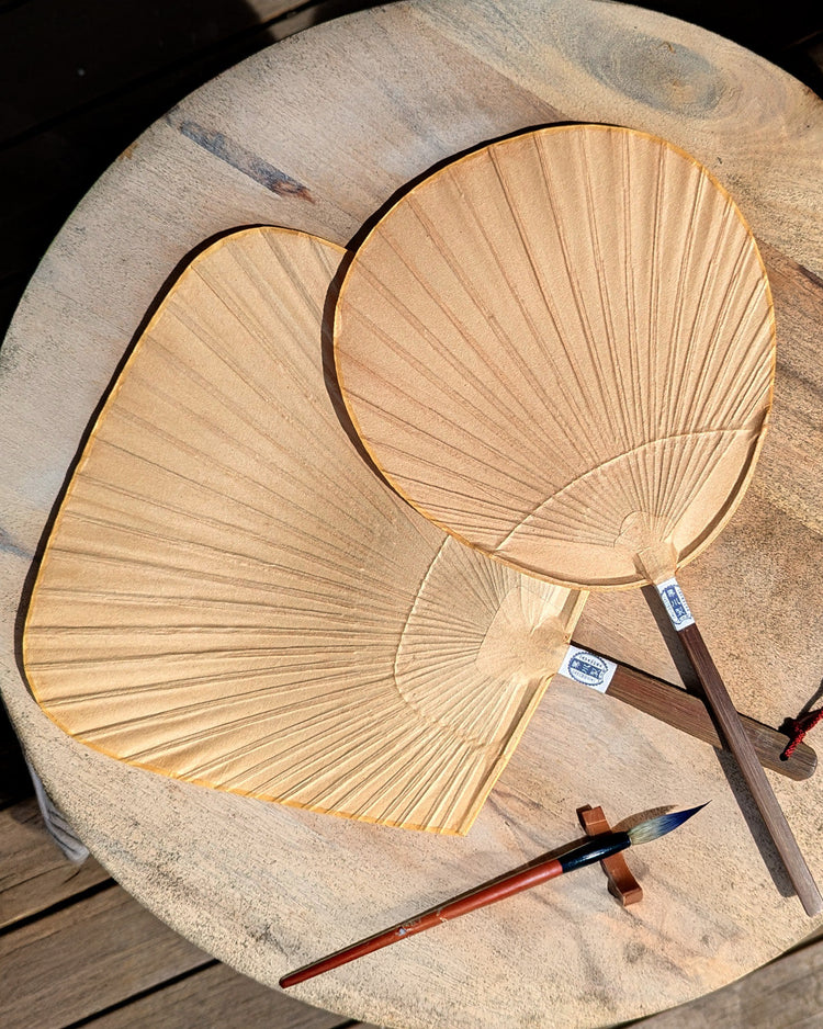two handmade traditional Japanese fans laid out on a table
