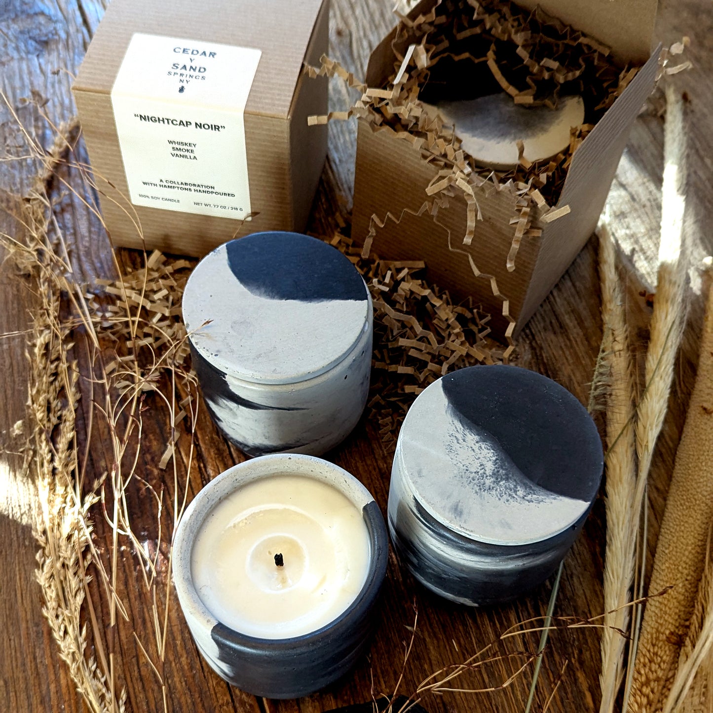 CEDAR Y SAND Nightcap Noir soy candle in marbled cement vessel with lid, displayed with kraft box and label for a rustic elegant presentation.