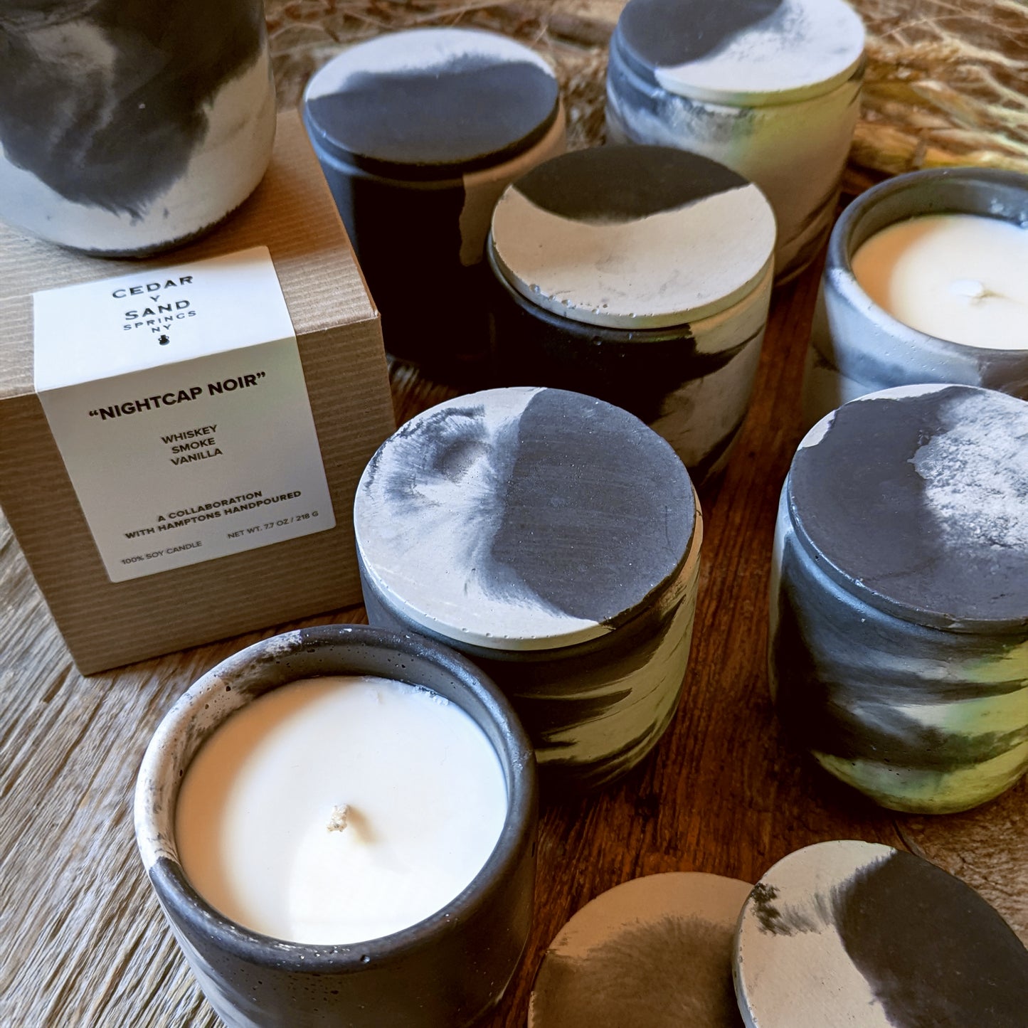 Collection of Nightcap Noir candles grouped together with packaging and labels showcasing handmade variations.