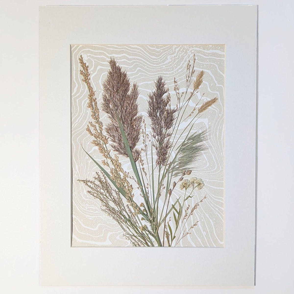 Windward original pressed botanical artwork featuring tall bronze and golden grasses gathered in East Hampton, arranged over hand-marbled Suminagashi paper in a white 12 x 16 inch mat.