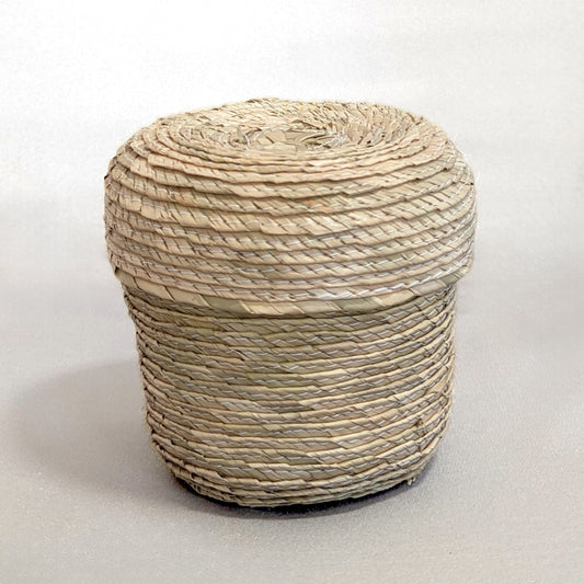 Lidded natural handwoven palm leaf basket on a white background