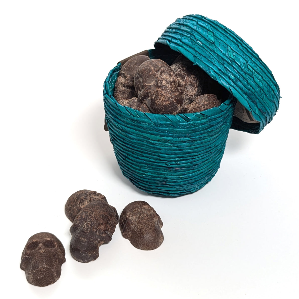 oped lid of teal palm leaf woven basket with cinnamon chocolate hand molded skulls spilling out