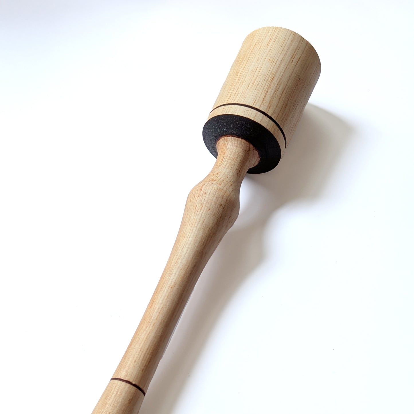 Narrow wooden pestle masher shown at an angle for darker accent details