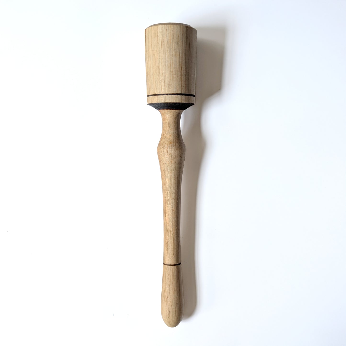 Hand carved narrower wooden pestle with burn accents details on a white background
