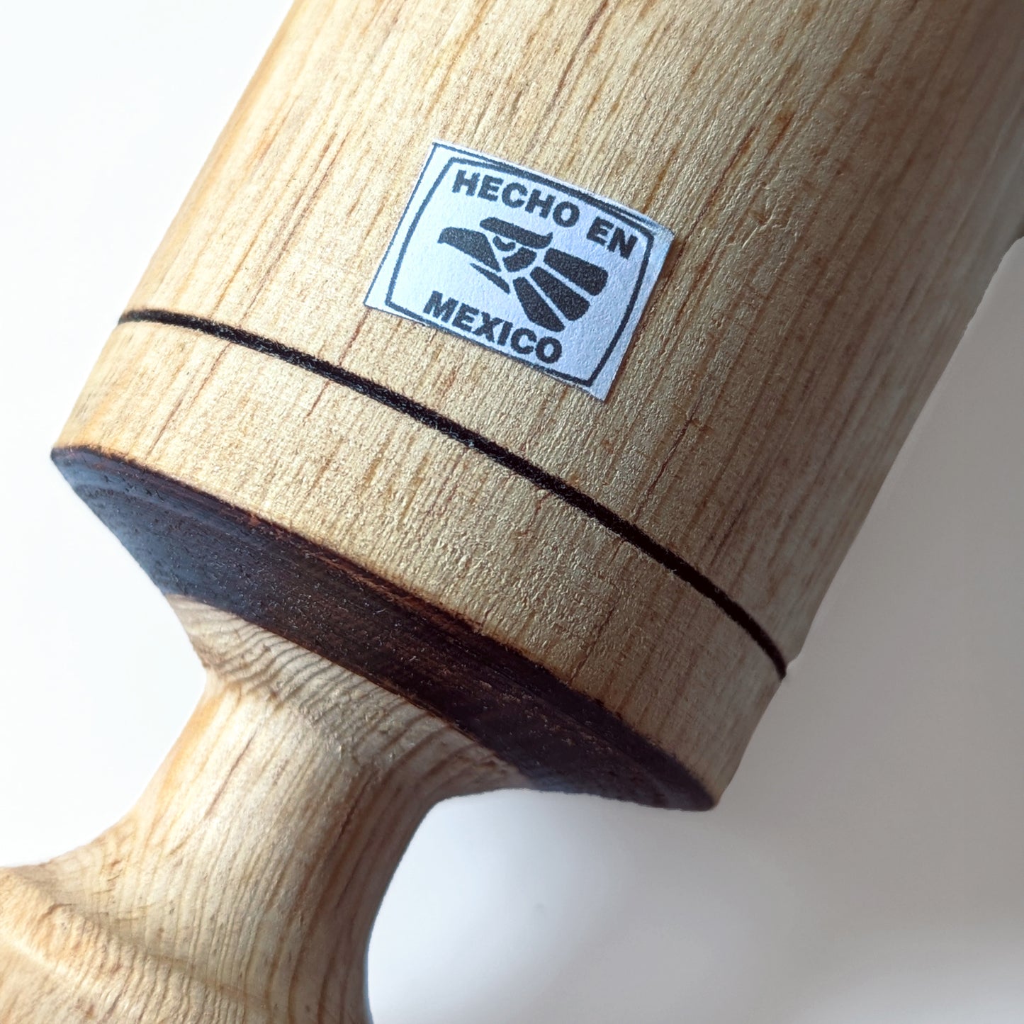 Close-up of wooden pestle masher with 'Hecho en Mexico' label on a white background