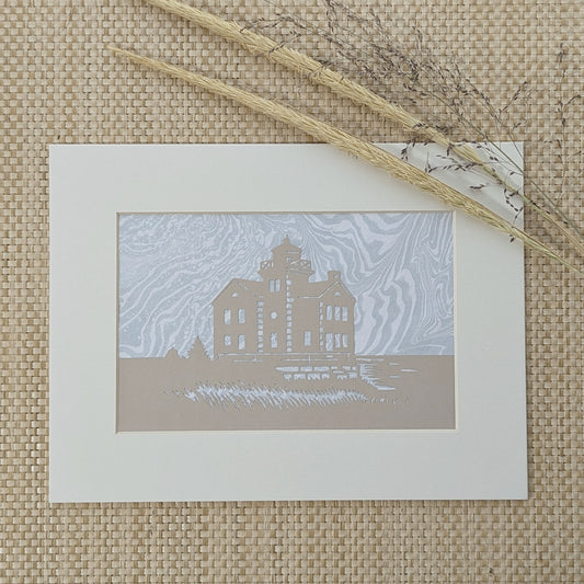 Earth-toned lighthouse silhouette artwork with fog-hued marbled ink background, styled with natural woven texture and dried dune grasses.