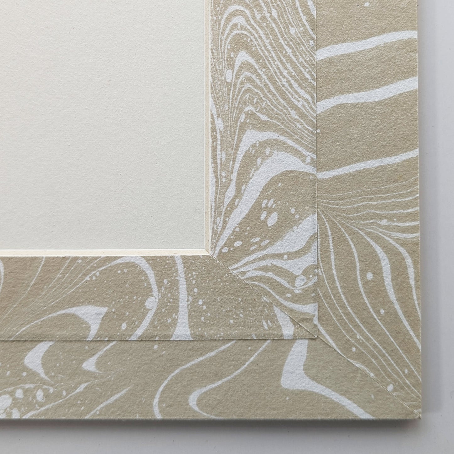 Close view of tan and white suminagashi marbled Hosho paper mat around painting.