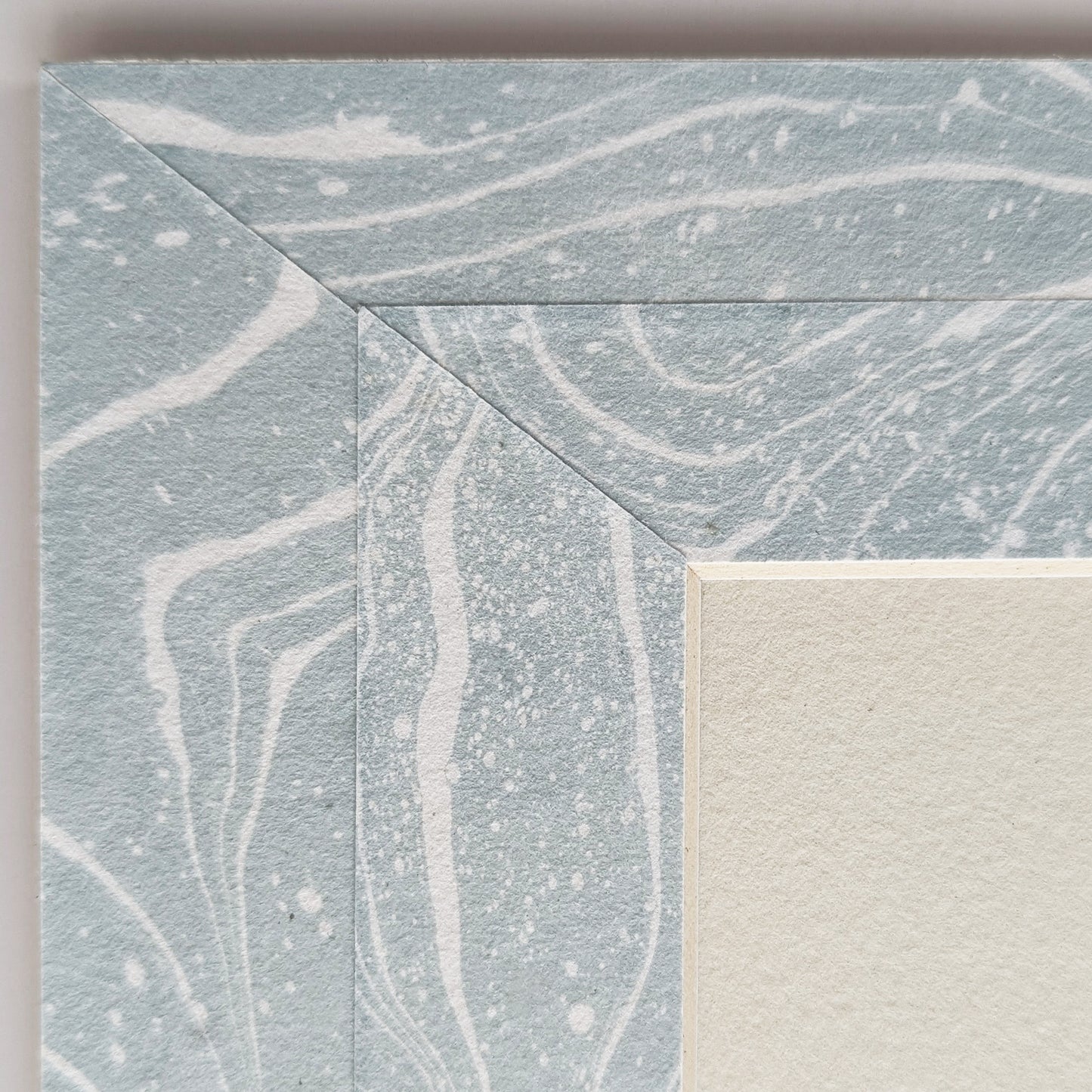 Close view of soft blue and white suminagashi marbled Hosho collage paper mat around painting.
