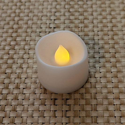 Autumn Glow LED tealight with warm amber flame on woven surface.