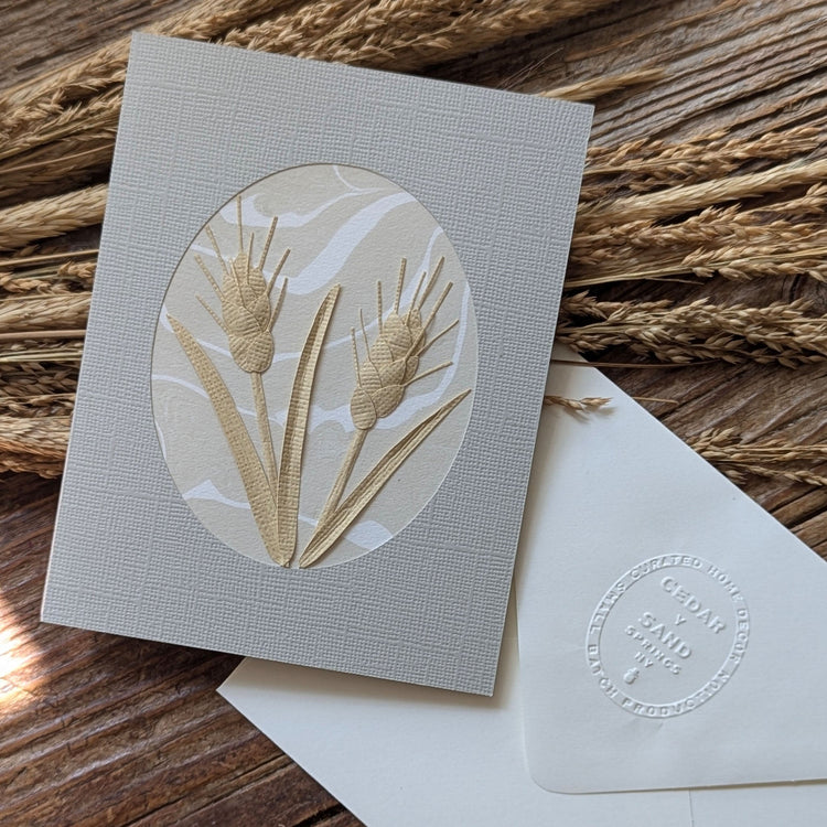 Handmade Wheat Suminagashi notecard styled among dried wheat, featuring dimensional hand-cut paper botanicals by CEDAR Y SAND.