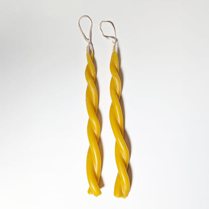 Two hand-dipped Twin Flame beeswax candles with twisted forms and cotton wicks, shown on a white background highlighting their natural golden hue and smooth finish.