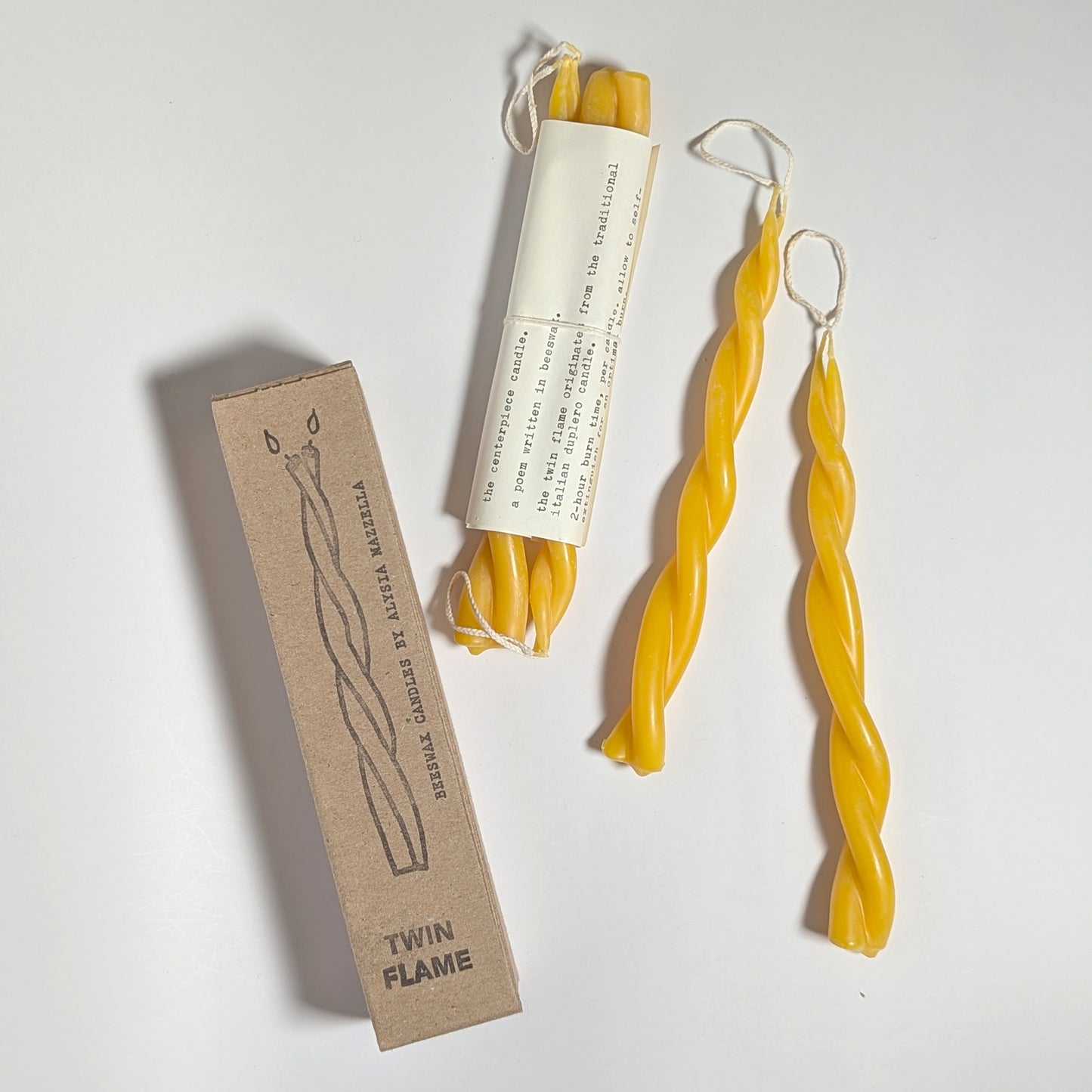 Twin Flame beeswax candles displayed with their minimalist kraft box packaging, featuring hand-drawn candle illustration and natural labeling.