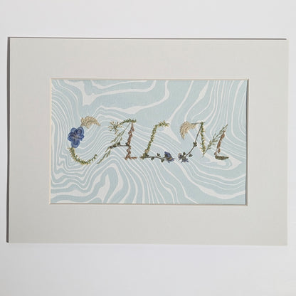 Pressed floral word “CALM” formed with real botanicals on hand-marbled Suminagashi paper, matted artwork by CEDAR Y SAND