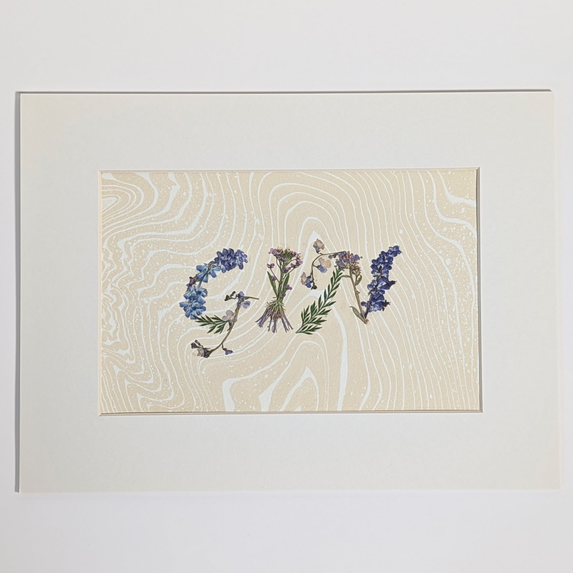 Pressed floral word “GIN” made with pressed botanicals on Suminagashi marbled paper, unique handmade word artwork