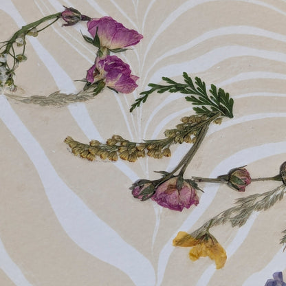 Close-up of pressed floral word “HOME” formed with natural botanicals on Suminagashi marbled paper