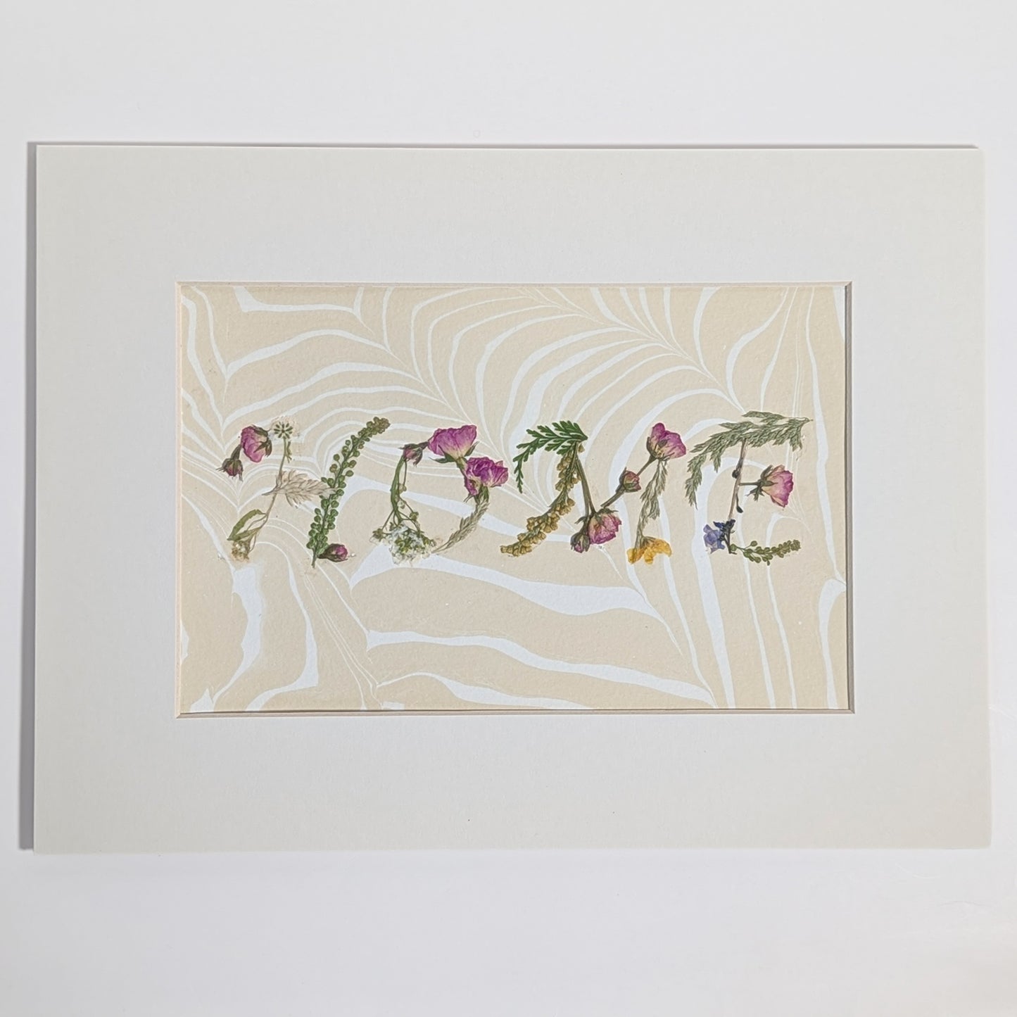 Pressed floral word “HOME” created with natural botanicals on Suminagashi marbled paper, one-of-a-kind matted art