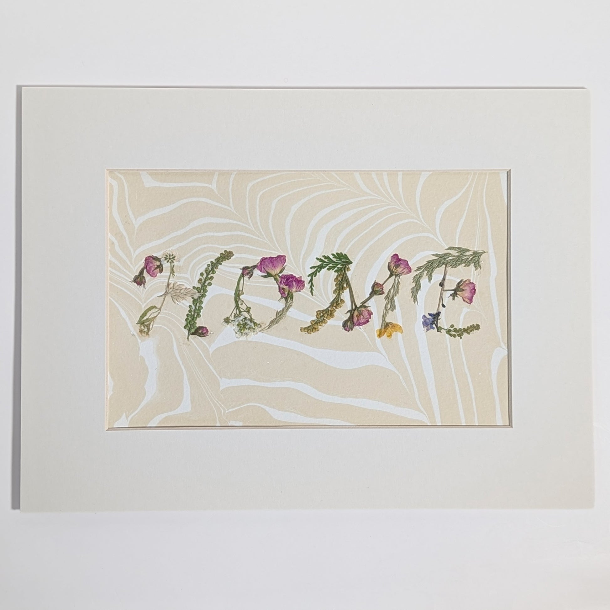 Pressed floral word “HOME” created with natural botanicals on Suminagashi marbled paper, one-of-a-kind matted art