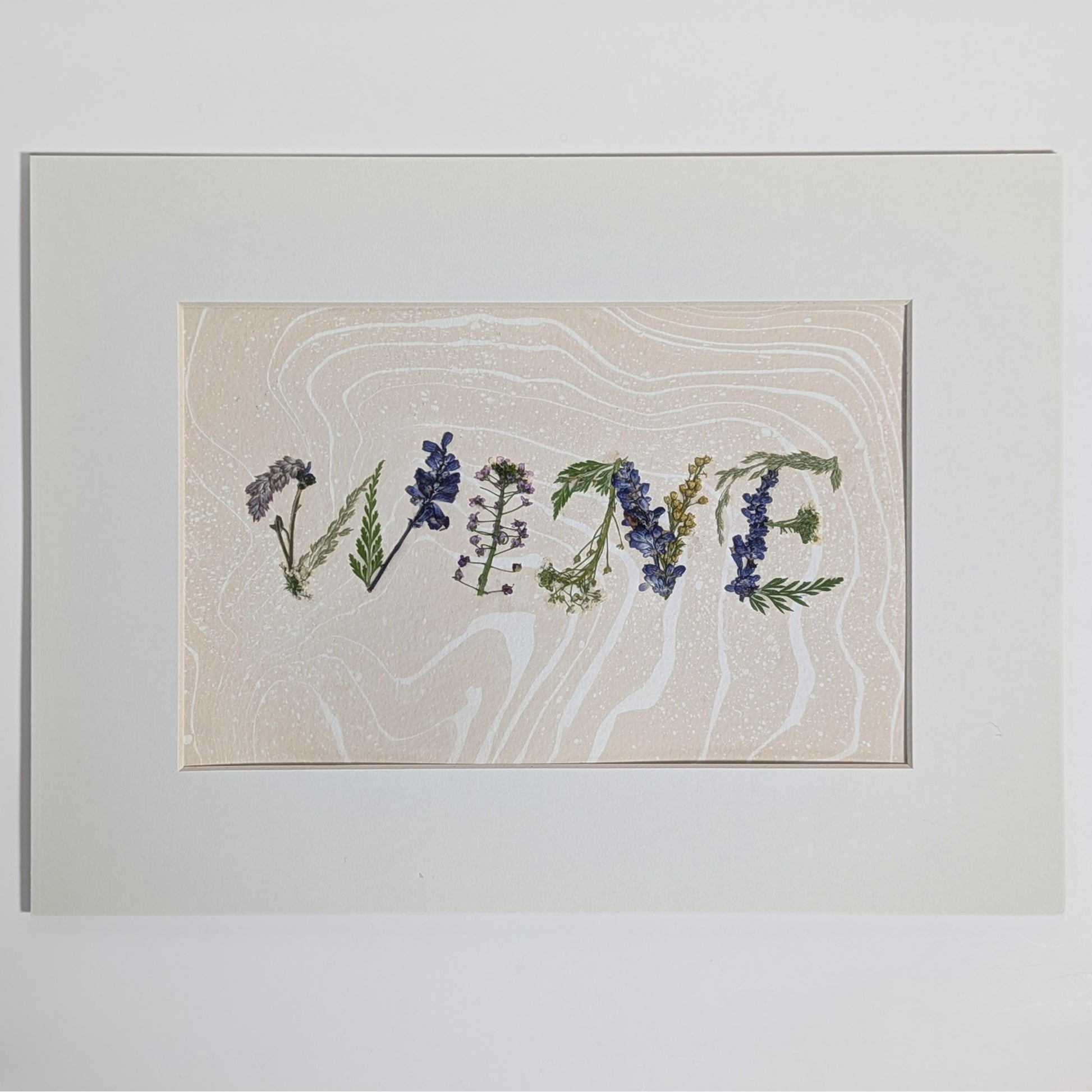 Pressed floral word “WINE” composed from real flowers on hand-marbled Suminagashi paper, framed botanical word art