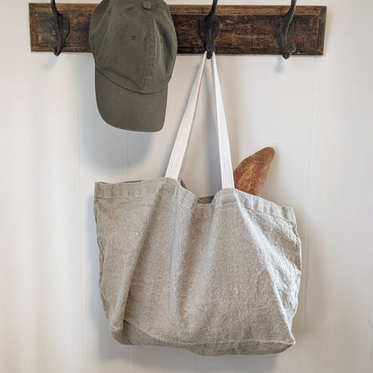 Charvet Éditions Doudou linen tote in Natural hanging on wall hook styled with hat and everyday essentials
