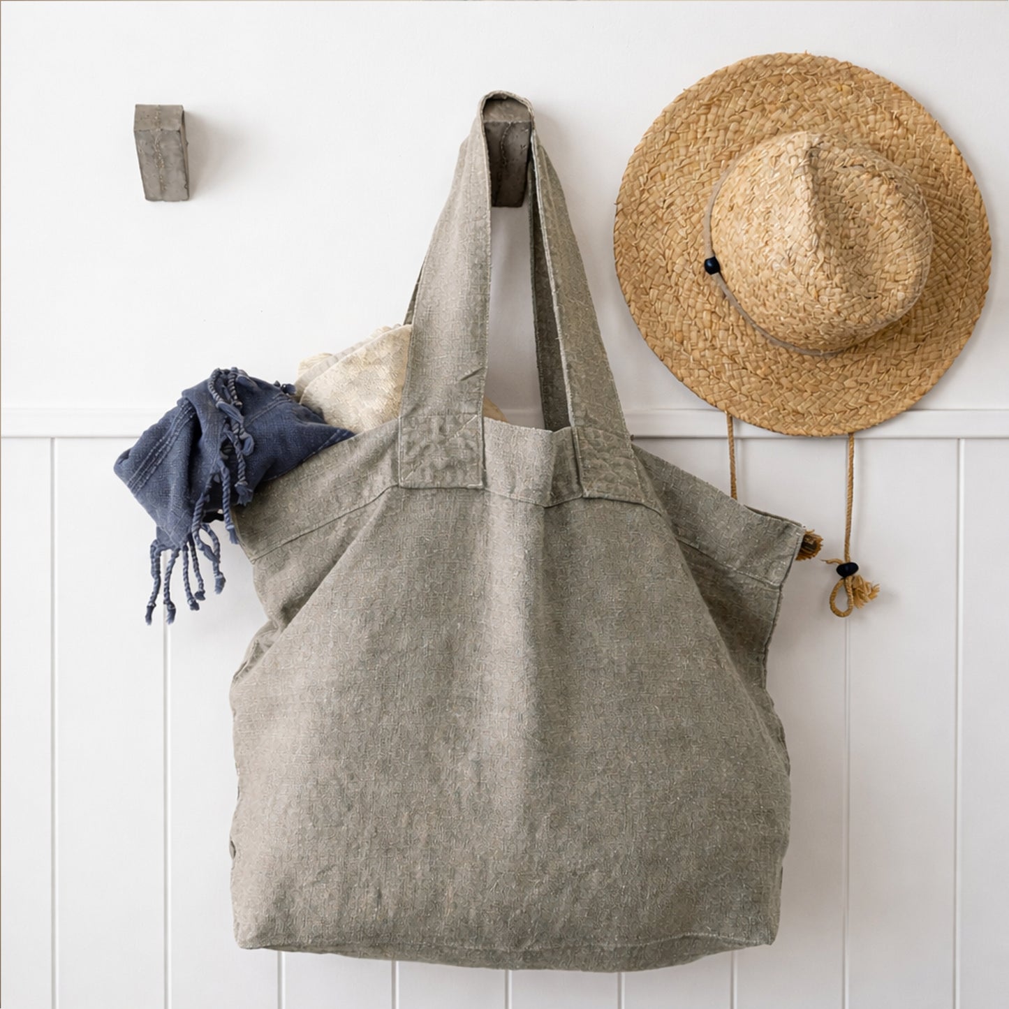 Charvet Escapade Natural linen tote hanging on wall with straw hat and casual styling