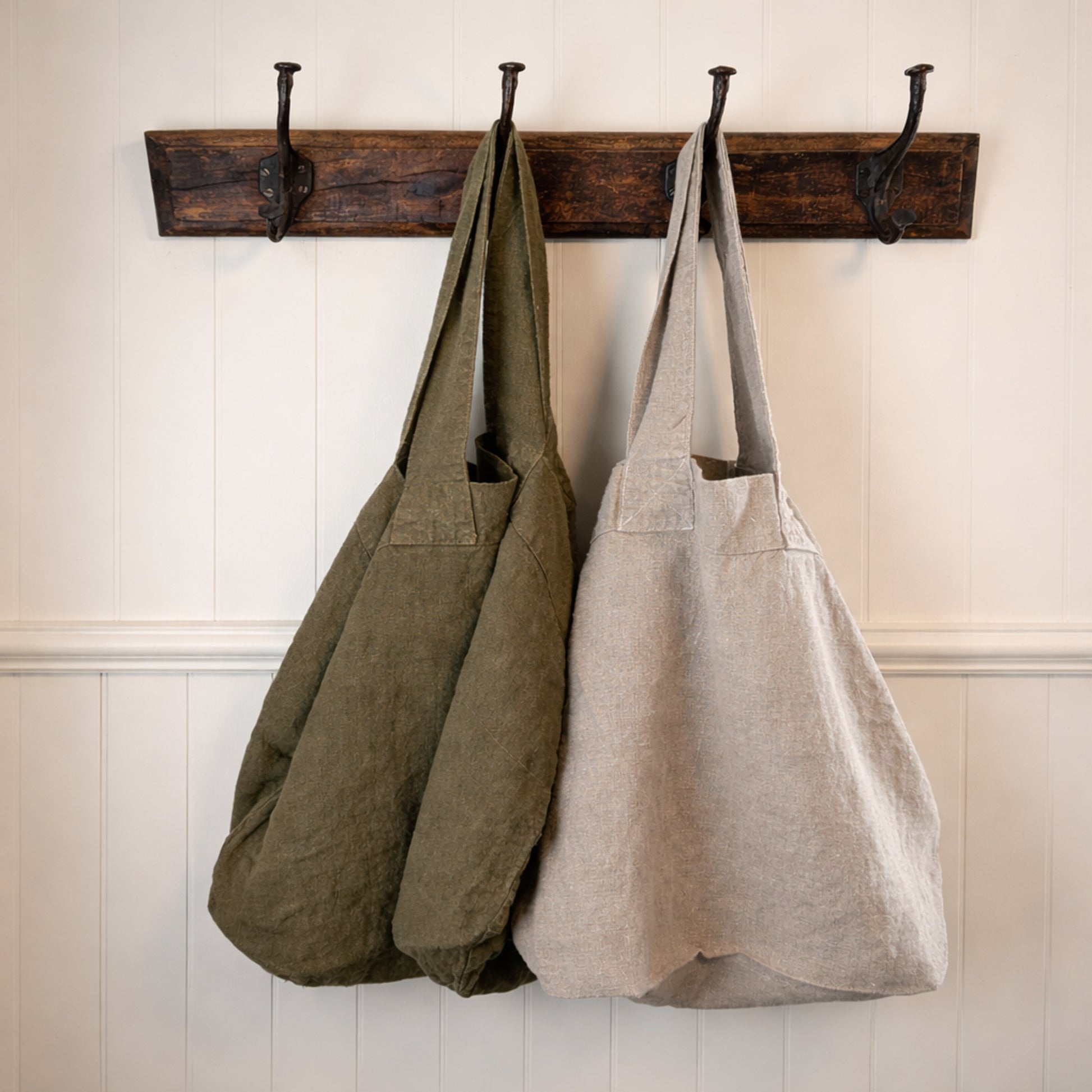 Charvet Escapade tote bags in Olive and Natural hanging side by side on rustic wall hooks