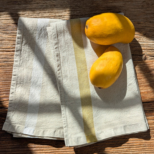 Charvet Éditions Phenix linen-cotton kitchen towel in Bergamot stripe styled with fresh mangos on rustic wooden table