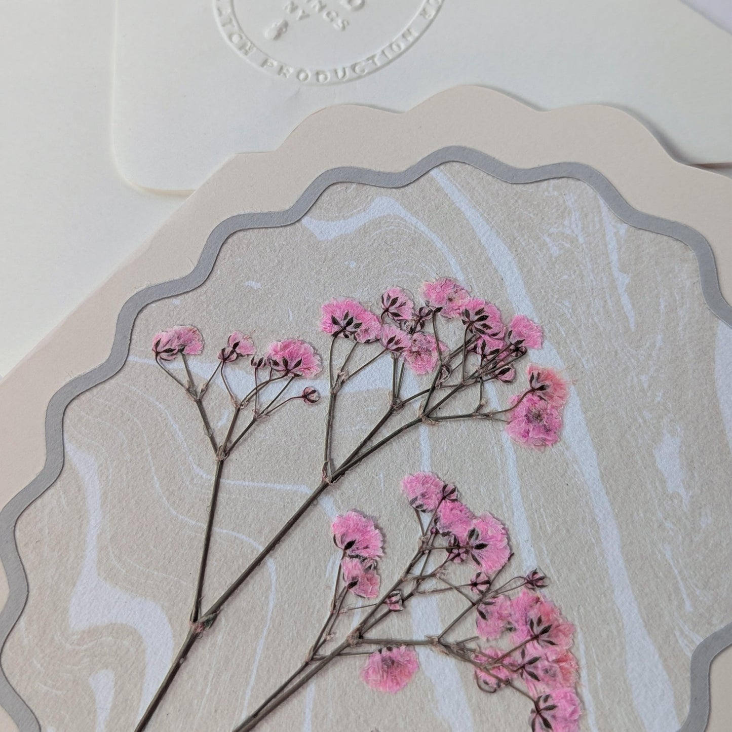 Close-up of pressed pink florals layered over marbled washi paper on Flora of Affection notecard