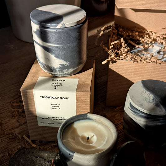 Close-up of Nightcap Noir candle in sunlight, showing hand-poured cement texture and soy wax surface in wabi-sabi style.