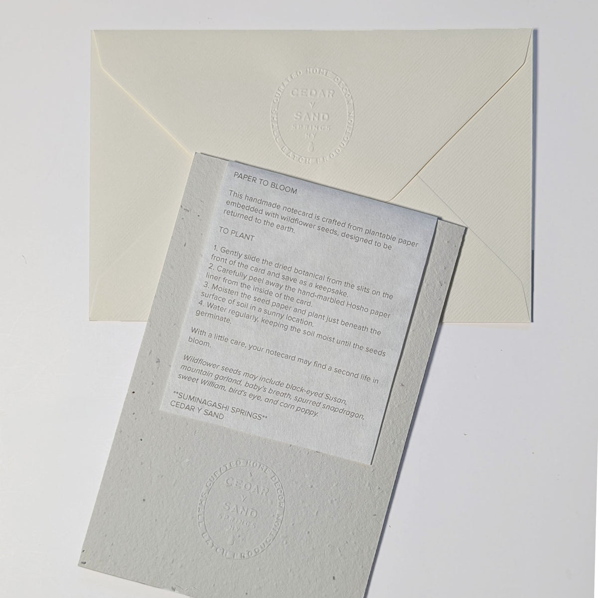 Back of Poetry in Bloom seed paper notecard with CEDAR Y SAND embossed insignia and removable insert explaining how to plant the wildflower seed paper.
