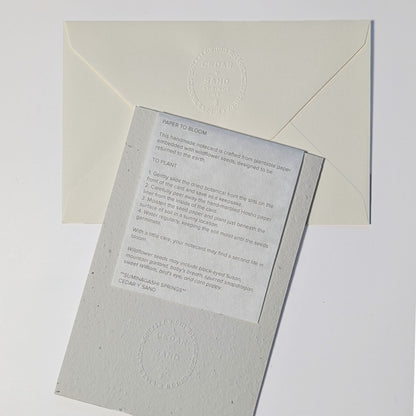 Back of Poetry in Bloom seed paper notecard with CEDAR Y SAND embossed insignia and removable insert explaining how to plant the wildflower seed paper.