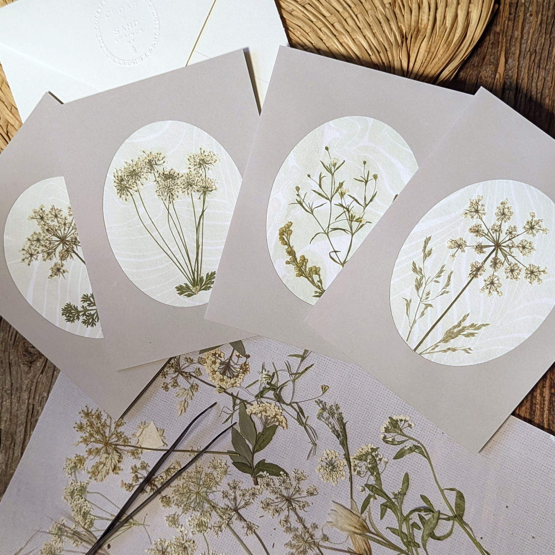 Suminagashi pressed flora notecards with meadow sprigs, styled with dried wildflowers and embossed envelopes on wood surface