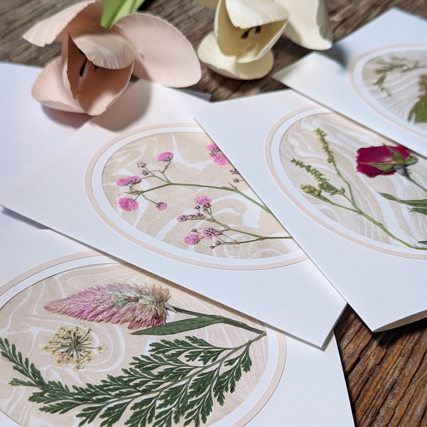 Close-up of Suminagashi pressed flora notecards featuring various wildflower arrangements on marbled paper with soft blush cameo borders