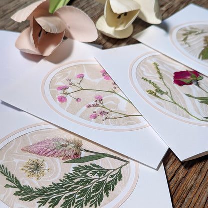 Close-up of Suminagashi pressed flora notecards featuring various wildflower arrangements on marbled paper with soft blush cameo borders