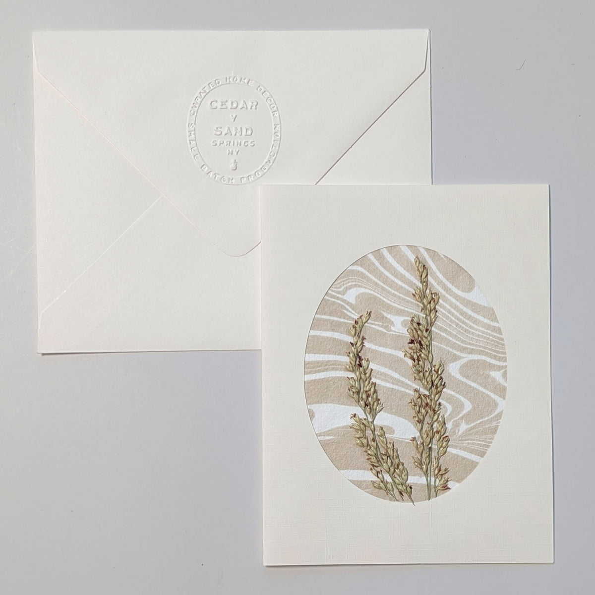 Handmade Walking Dunes Dunegrass notecard with pressed dune grasses layered over neutral hand-marbled Suminagashi paper in an oval aperture.