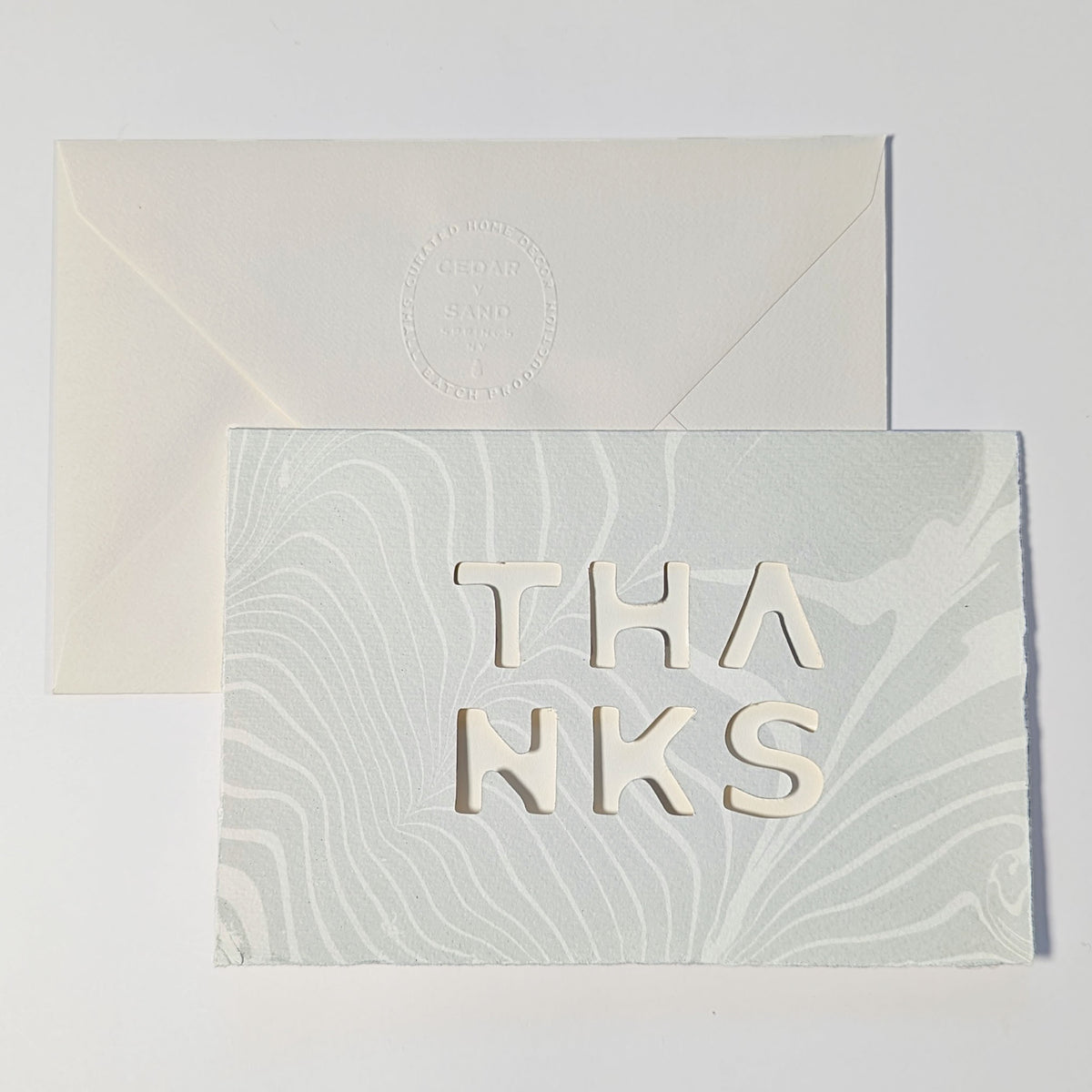 Suminagashi Springs Thanks Notecard in Mist, featuring pale blue-gray marbling, cut-out typography and natural Fabriano paper.