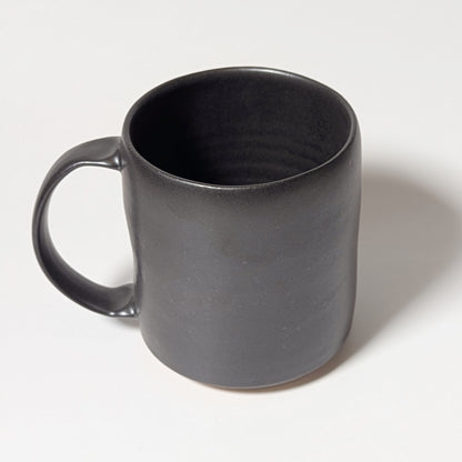 Front view of black handmade ceramic mug with softly tapered rim and balanced form