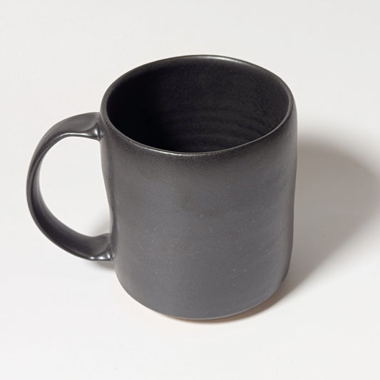 Front view of black handmade ceramic mug with softly tapered rim and balanced form
