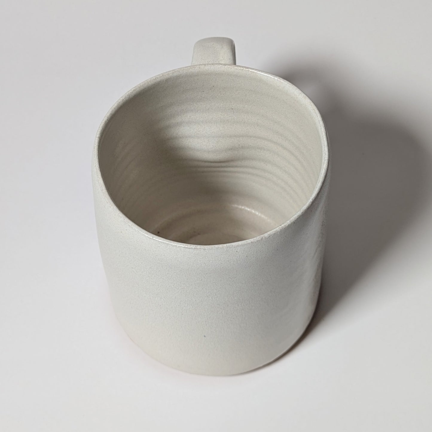 Close-up of off-white mug handle showing thumb grip and ergonomic indentation