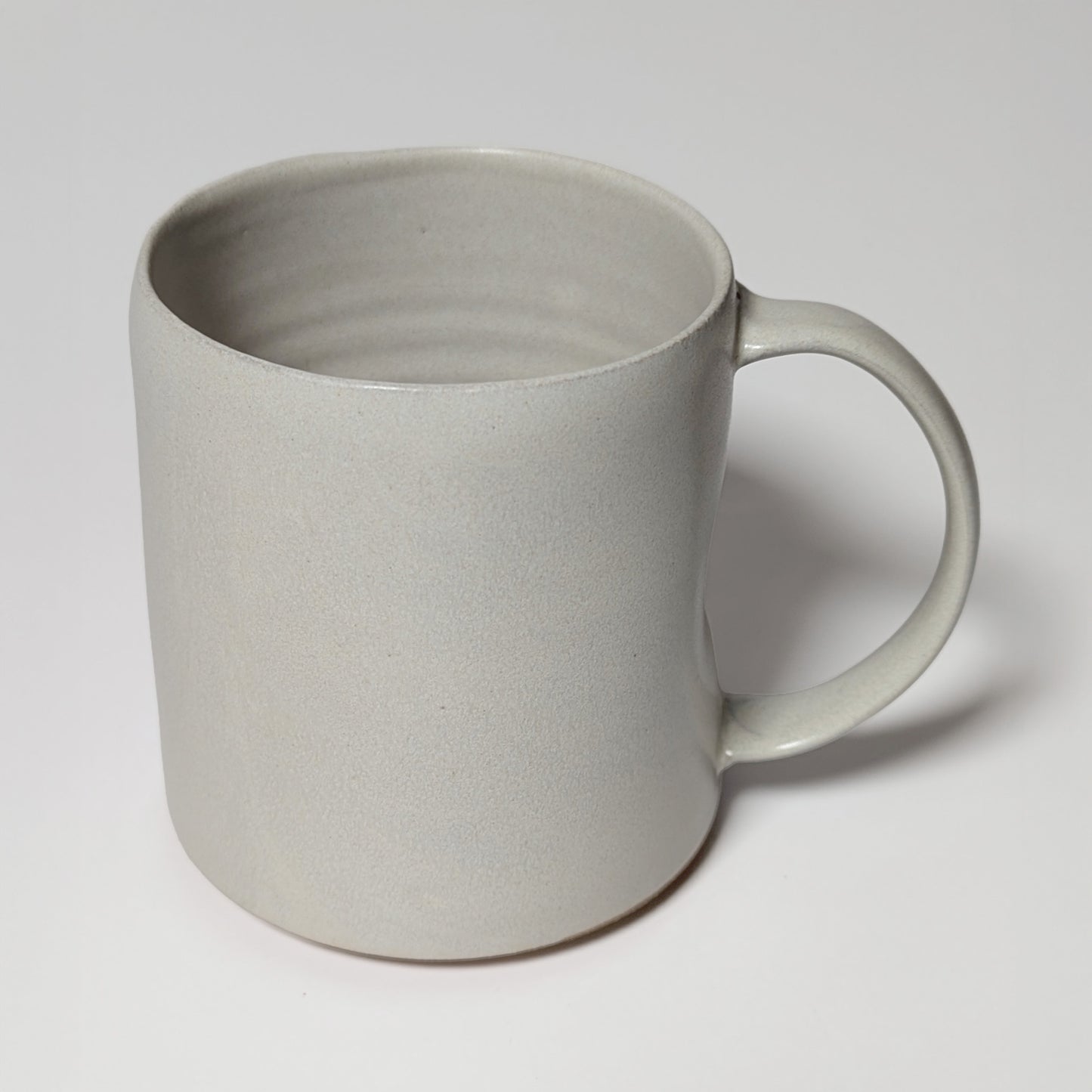 Front view of off-white stoneware mug with matte glaze and gently tapered lip