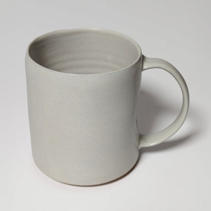 Front view of off-white stoneware mug with matte glaze and gently tapered lip