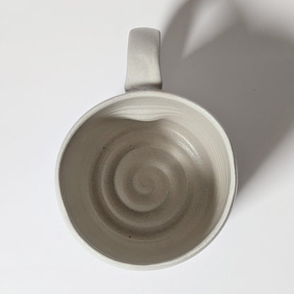 Top-down view of off-white ceramic mug showing spiral wheel marks inside