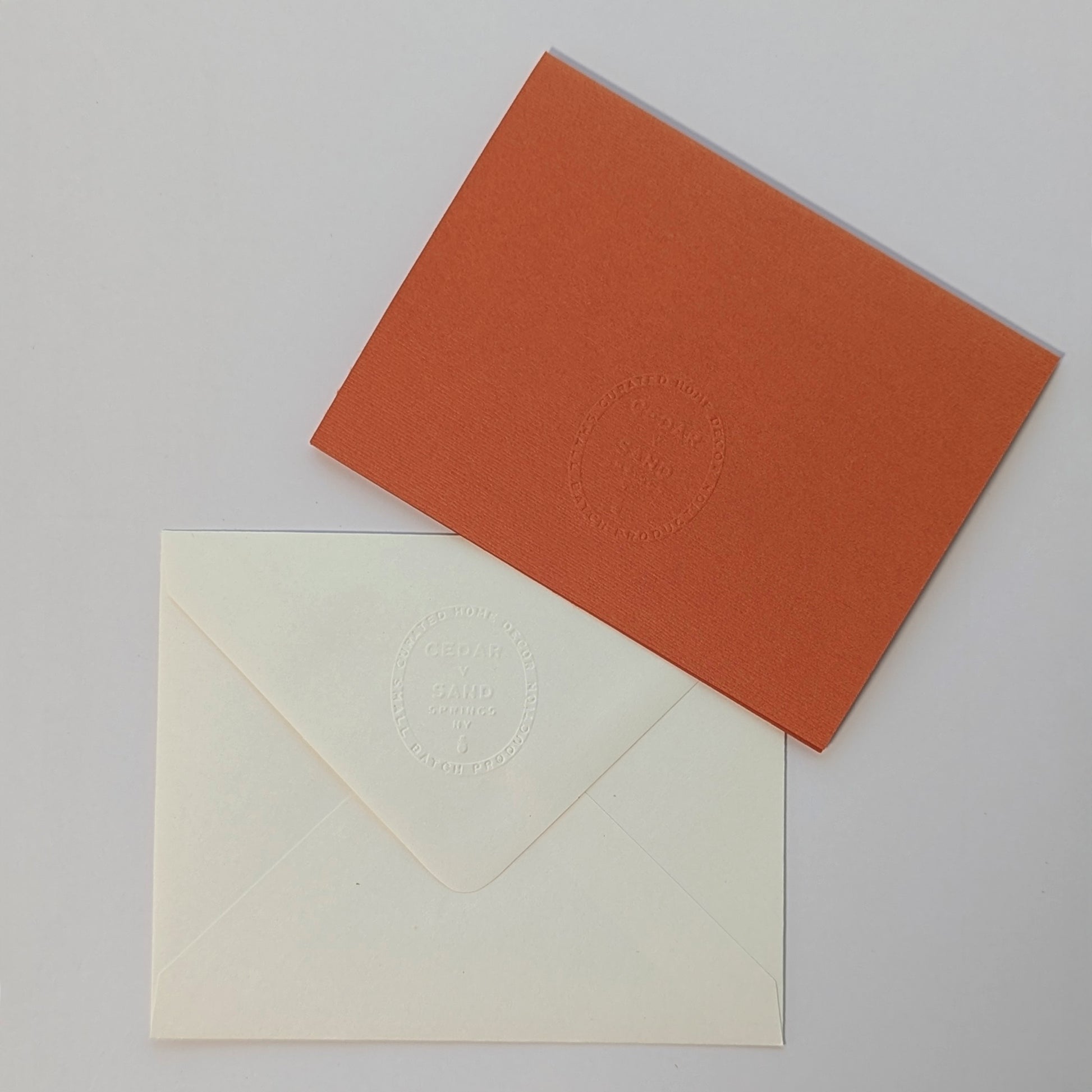 Back of Gourd Out notecard and cream envelope with embossed CEDAR Y SAND insignia on textured cardstock.