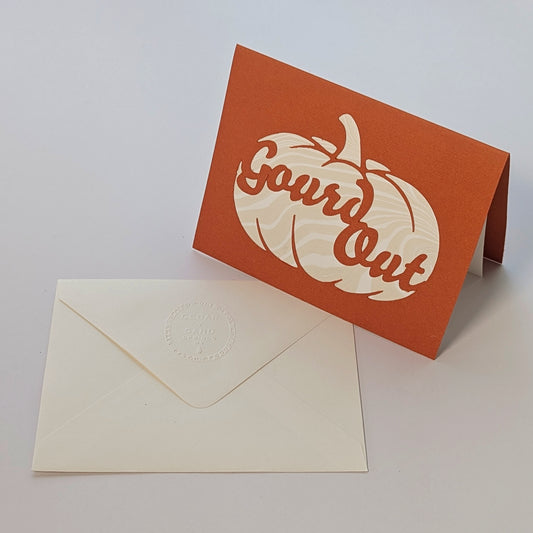 Pumpkin-colored Gourd Out notecard standing beside matching embossed envelope, revealing marbled suminagashi paper detail.