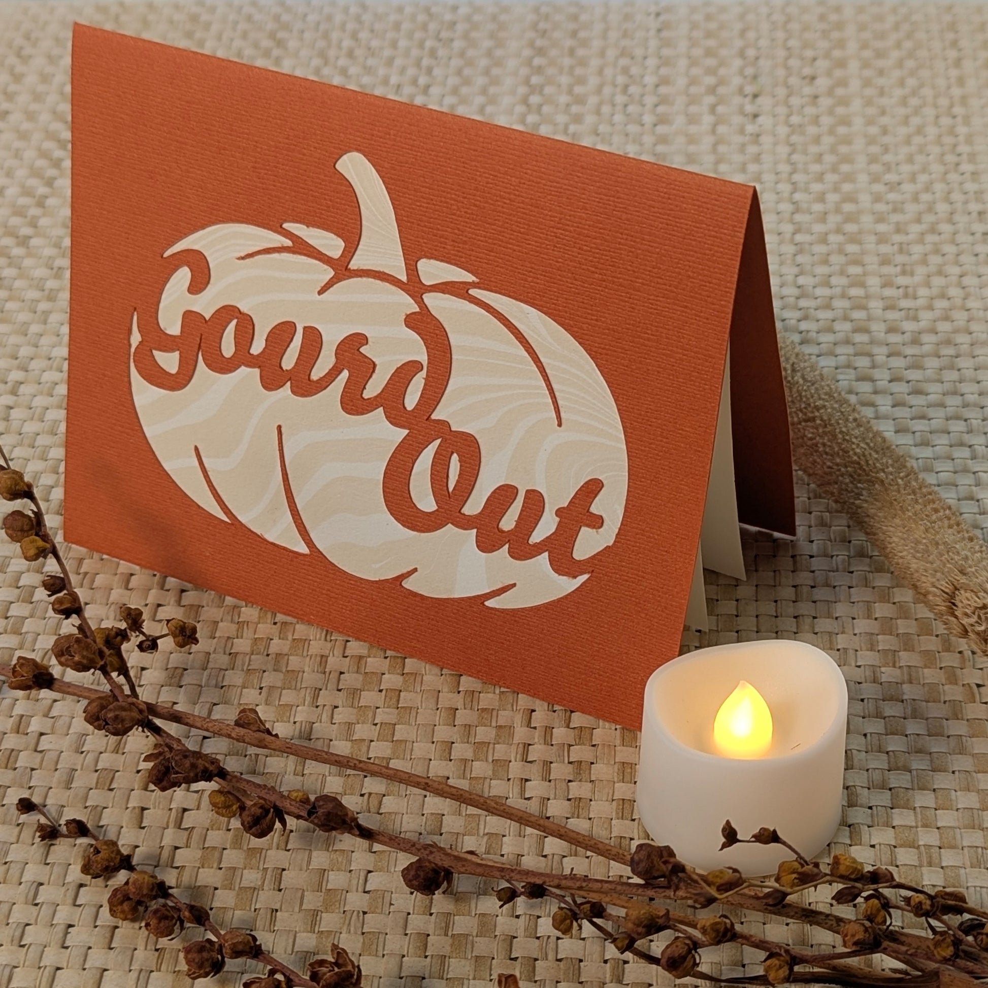 Pumpkin orange Gourd Out notecard with marbled paper cut-out, shown glowing beside an LED tealight and fall stems.