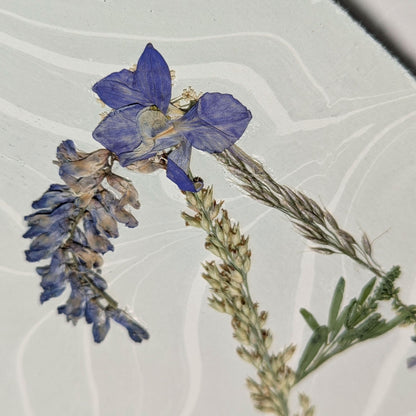 close-up  of Pressed floral “A2” initial notecard with neutral grasses and violet flora  on marbled Suminagashi paper, handmade on Fabriano Medioevalis cardstock