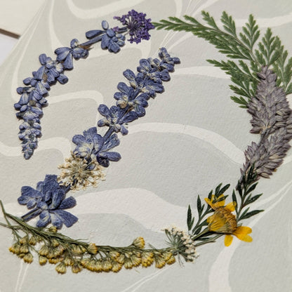 Pressed floral “D” initial notecard with delicate wildflowers on marbled Suminagashi paper, handcrafted on premium Italian cardstock