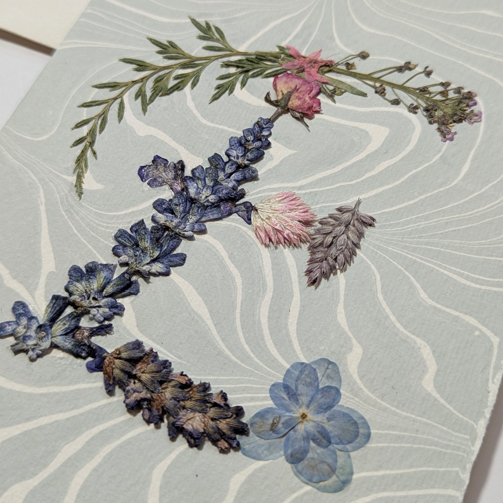 Botanical “E” initial notecard with pressed florals on soft blue Suminagashi marbled paper, artisan handmade on premium Italian cardstock