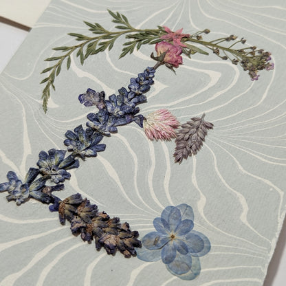 Botanical “E” initial notecard with pressed florals on soft blue Suminagashi marbled paper, artisan handmade on premium Italian cardstock