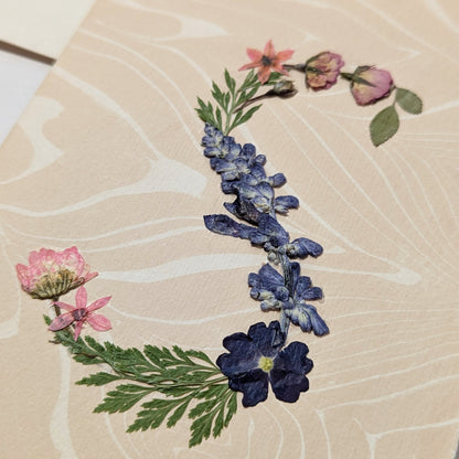 Pressed floral “S” initial notecard with blue and pink flowers on marbled Suminagashi background, handmade on Fabriano Medioevalis paper