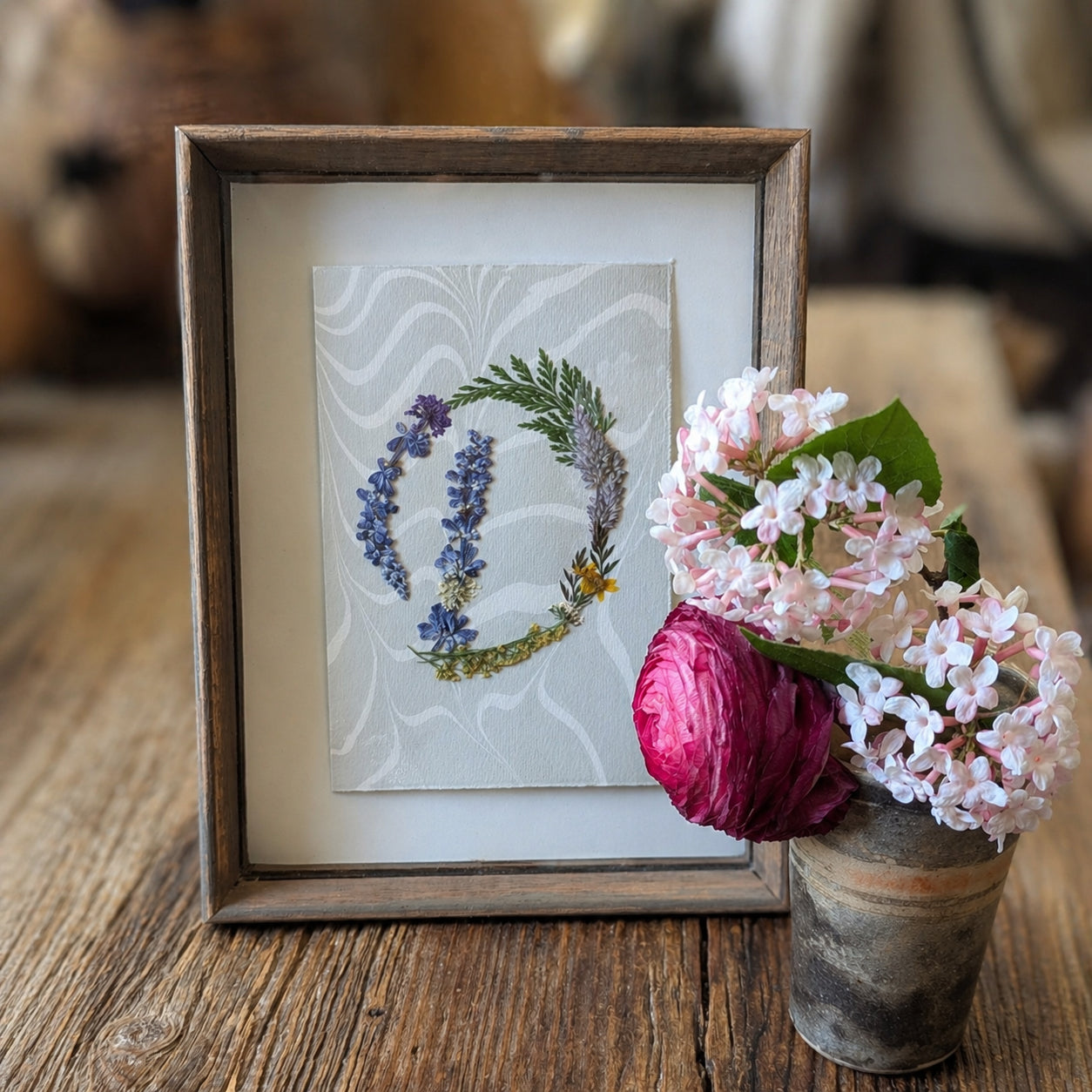 Framed pressed floral initial artwork with fresh flowers in vase, handcrafted botanical notecard displayed as wall art